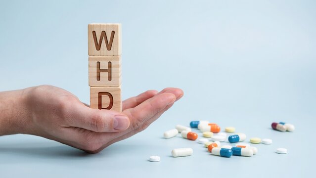 Hand holding colorful pills and capsules with WHD letters on palm minimal health concept
