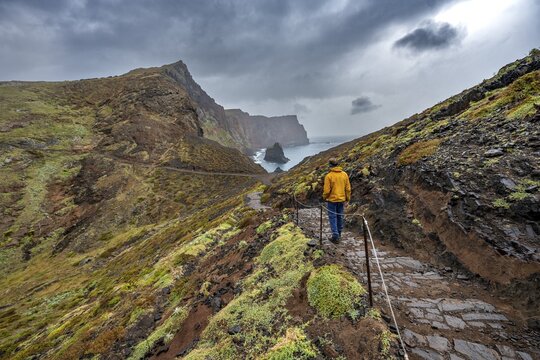 Hikers on trail at rocky headland, coastal landscape with red cliffs and sea, rugged coast with rock formations, Cape Ponta de S&atilde;o Louren&ccedil;o, Madeira, Portugal