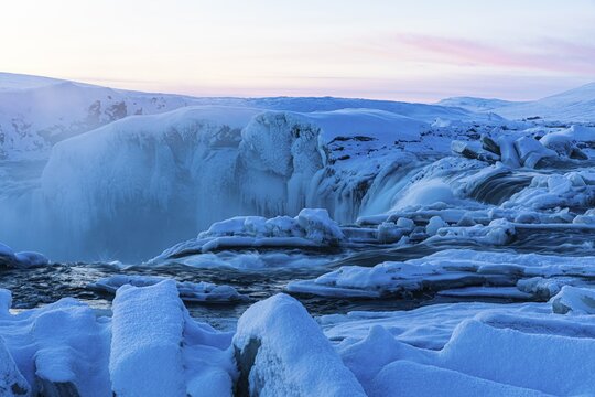 Icefall at the edge of the Godafoss waterfall at dawn, snow-covered landscape, Northern Iceland Eyestra, Iceland
