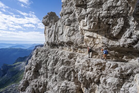 Two mountaineers on an exposed rock band in the secured via ferrata Bocciere Centrale, Brenta Mountains, Brenta-Adamello Natural Park, Trentino, Italy