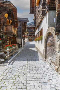Paved footpath surrounded by old wooden houses, flower boxes on balconies and windows, historic village centre, Grimentz, Val d'Anniviers, Valais Alps, Canton Valais, Switzerland