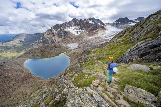 Mountaineer on hiking trail in dramatic high mountain landscape, view of mountains with mountain lake Vogelh&uuml;ttensee and glacier &Uuml;beltalferner, Stubai Alps, South Tyrol, Italy