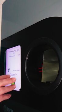 Close up of a hand inserting aluminum cans into a reverse vending machine for recycling, receiving a monetary deposit in return, showcasing a circular economy and responsible consumption