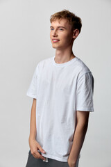 Obraz premium Casual, young man in a white tshirt posing in a studio, relaxed stance, minimalist fashion, clean background, soft light, versatile wardrobe for everyday style