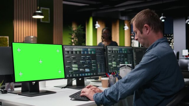 Green screen PC used by admin in office working to fix bugs in AI system with debugging and troubleshooting context for chroma key screen replacement.