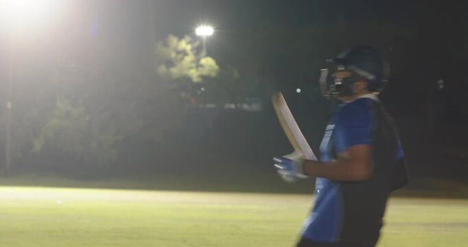 batsman swinging bat clearing boundary, male teammates hugging