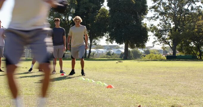 Stepping male teammates performing cone agility drill on sports field, cones, copy space