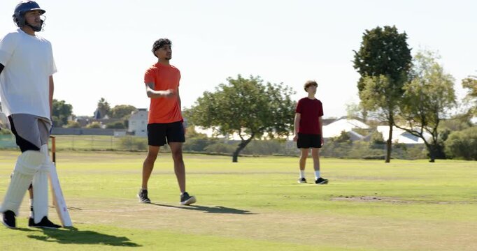 Man hitting wicket on cricket pitch, picking ball, running on coach nod as fielder misses