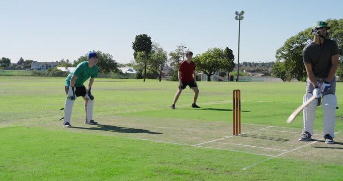 Bowler running on pitch, teenage wicket-keeper diving gathering ball at stumps blocking run