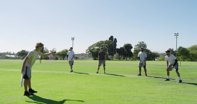 Playing diverse male teammates batting and fielding on park field, bat and stumps, copy space