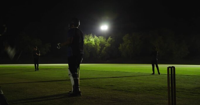 African american batsman after delivery swinging bat missing ball walking, floodlights, copy space