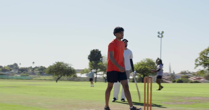 Diverse teammates releasing red cricket ball and practicing catching, throwing on cricket ground
