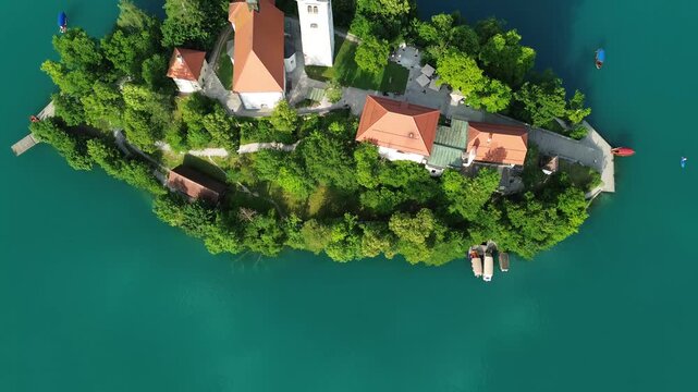 Top-down aerial view of Bled Island and the Assumption of Mary Church on Lake Bled, Slovenia. Cinematic drone footage of the historic island surrounded by vibrant turquoise water in summer.