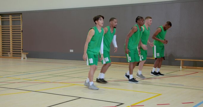 Entering gym male basketball players doing toe touch along sideline and picking up basketball