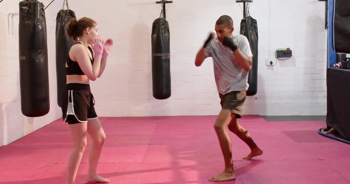 Diverse sparring partners feinting, trading light jabs with pink gloves on red mat, high-fiving