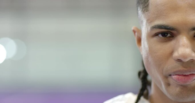 African american man staring into camera, shifting smirk into smile, calm at gym, copy space