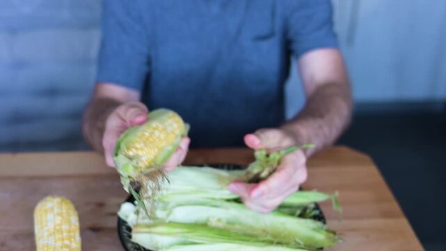 Man peeling fresh corn husk from cob during kitchen food Full HD preparation video