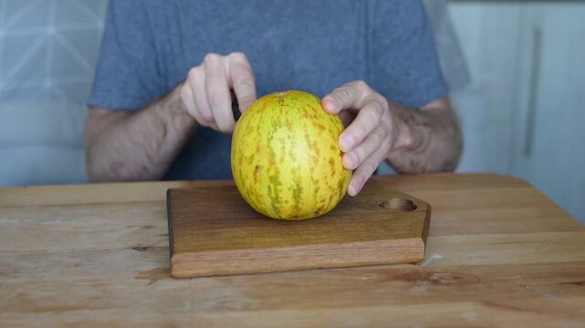 Man placing and cutting ripe yellow melon on wooden board in kitchen video Full HD