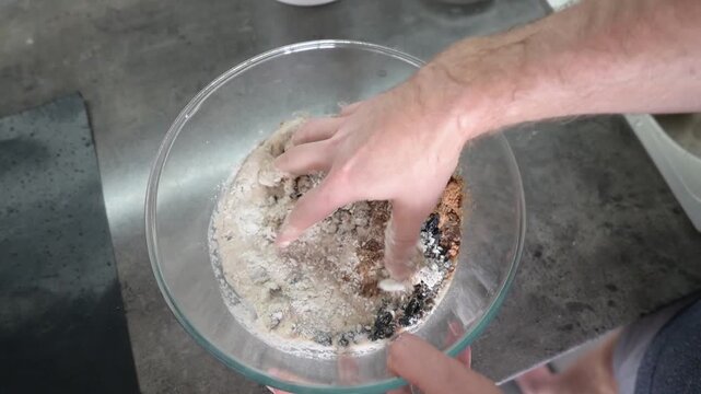 Hand mixing raisin dough ingredients in glass bowl for homemade baking video Full HD