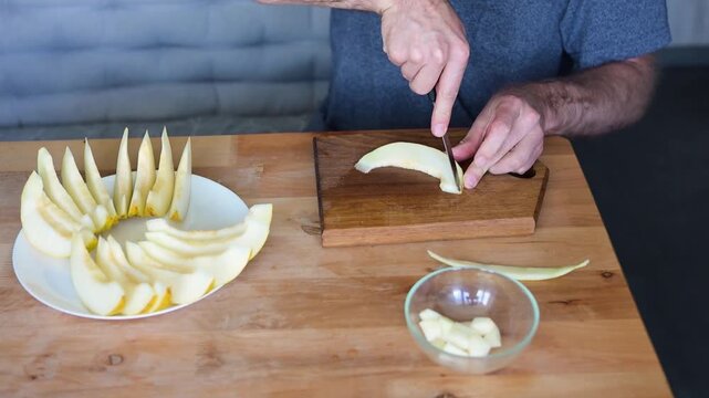 Man cutting melon flesh into cubes beside prepared fruit platter in kitchen video Full HD