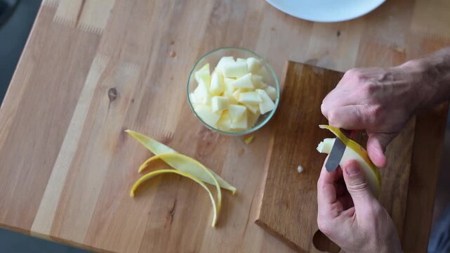Man peeling fresh melon slice over wooden cutting board in home kitchen video Full HD preparation