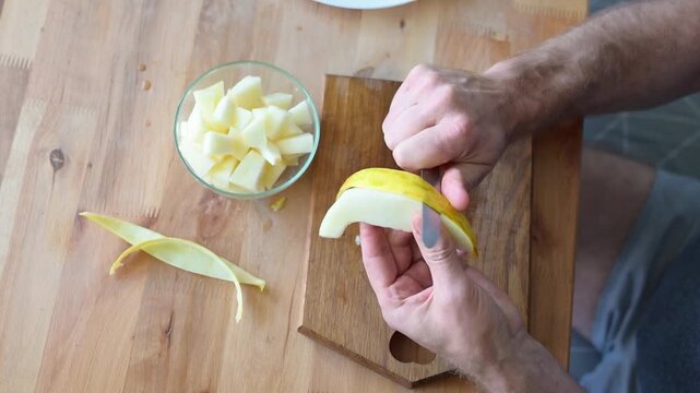 Man peeling fresh melon slice over wooden cutting board in home kitchen preparation video Full HD