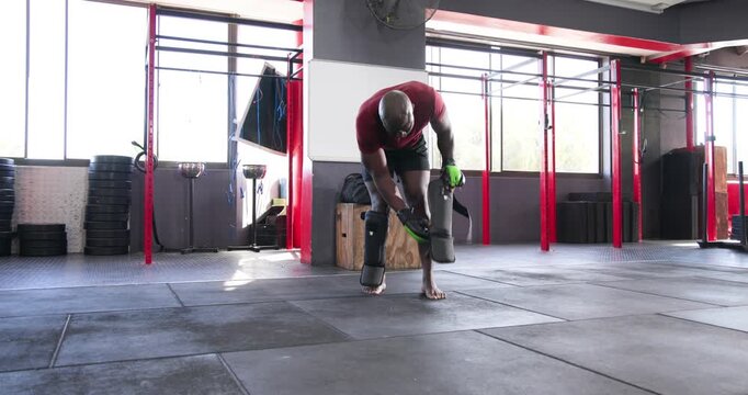 Diverse males holding kick shields while fitting and testing shin guard before taking stance