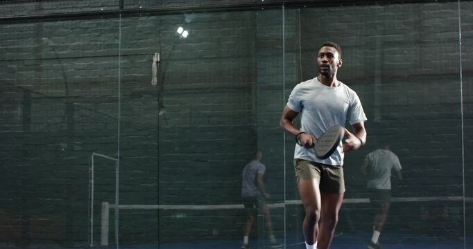 After serve diverse male friends lunging, rallying with paddles on padel court