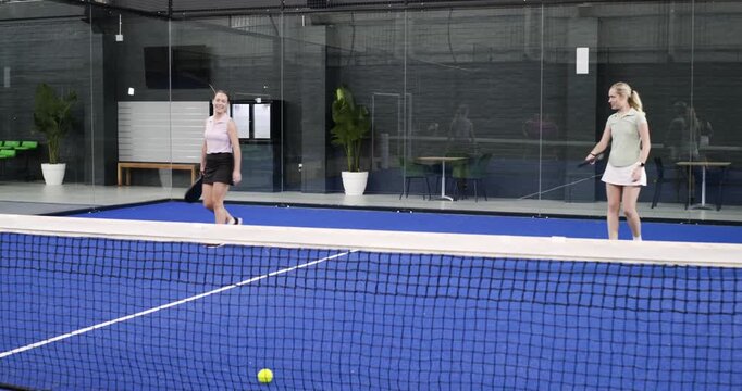 Female athletes chasing volley on padel court undercutting ball serving return copy space