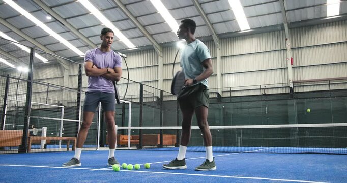 After picking ball, african american player practicing volley on padel court for skill training