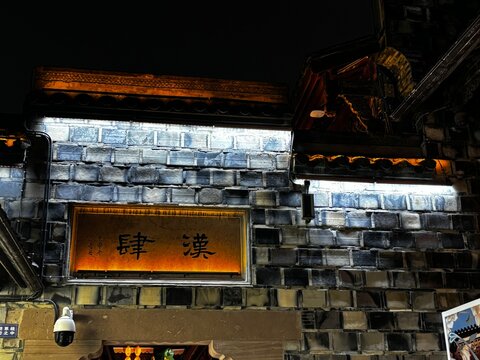 Chengdu, China - November 8, 2025: Close up night view focused on illuminated wooden Han Si sign on grey traditional brick wall at Jinli Ancient Street.