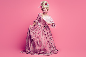 Fototapeta premium Full length photo of happy attractive lady dressed baroque costume waving hand fan copy space isolated pink color background