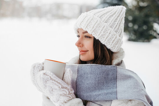 Beautiful Caucasian Woman Holding Warm Mug in Snowy Winter Wonderland