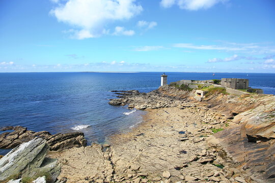 Kermorvan-Leuchtturm an der felsigen K&uuml;ste der Bretagne. Das historische Bauwerk steht auf einer Landzunge umgeben vom blauen Atlantischen Ozean unter strahlendem Himmel.