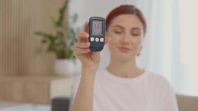 A woman shows her glucometer reading of 111 mg dL in a home environment. She discusses what this means for blood sugar levels and health management.