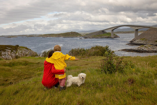 Family, kids and adults and a pet dog, enjoying the view of the Atlantic ocean road from one of the many car stops along the road