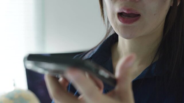 Business woman speaking to a smartphone on speaker mode, suitable for voice message, voice assistant, online communication, AI technology and mobile app concepts.