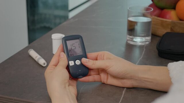Hands of a woman in a kitchen check the history of blood sugar results using a glucometer diary. The activity shows the importance of monitoring glucose levels daily.