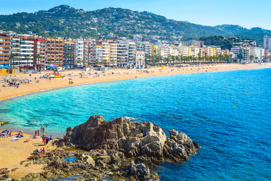 Beautiful coastal view of a sandy bay and turquoise sea with prominent rocks in Lloret de Mar on a sunny day, Costa Brava, Catalonia, Spain.