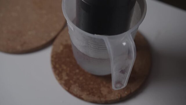 Hand cutting glass bottle using thermal shock with hot water and ice demonstrating diy upcycling craft and stress fracture physics lesson for homemade glass. Diy project for recycling, close-up.