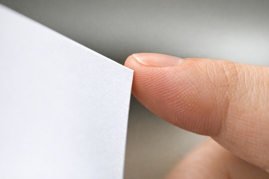 A person holding a piece of paper, possibly reading or referencing
