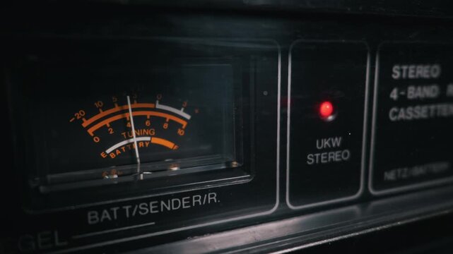 Macro close-up of a vintage radio analog tuning meter with a glowing red stereo indicator light. Concept of retro technology, nostalgic music appreciation, and classic analog audio broadcasting.