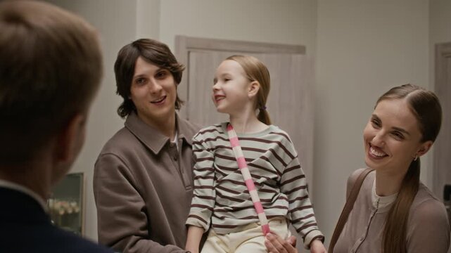 Over the shoulder view of family with child checking in at hotel reception desk, handing passports to receptionist. Video is perfect for family vacation ads and hospitality marketing campaigns
