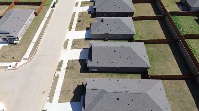 Master Planned Street Alignment show row of newly built homes lining clean concrete curb along Stud Dr. Dark brick facades, fresh turf, geometric roof lines, Aubrey Dallas Fort Worth metroplex, TX