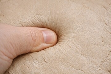 Fototapeta premium A person holds their finger on a piece of clay, preparing to shape or mold it