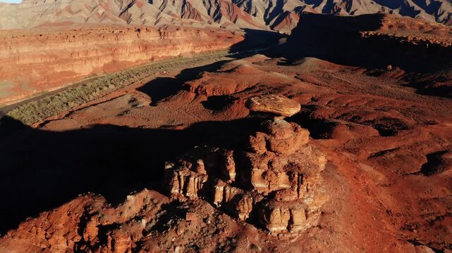 Drone aerial flying over the top of Mexican Hat Rock in southeastern Utah near golden hour.