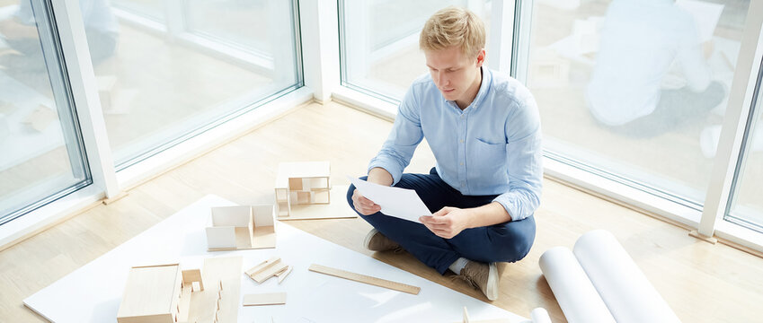 blank letter mockup Scandinavian man sunroom documents reading message minimalist Wider composition includes the surrounding environment and everyday lifestyle context young man sits among scattered