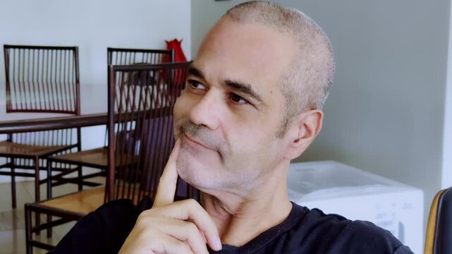 Slow motion close-up of a mature man with his hand on his chin, showing a skeptical smirk, pensive smile, or calculating expression. Ideal for strategy and doubt concepts