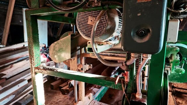 Industrial band saw machine with a sharp blade processing a large log in a woodworking factory