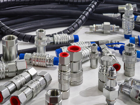Variety of metal fittings and hoses used in mechanical systems on a table in a workshop setting during daylight hours